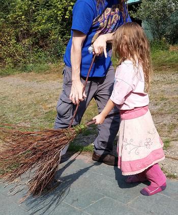 man and child sweeping with rustic handmade brooms