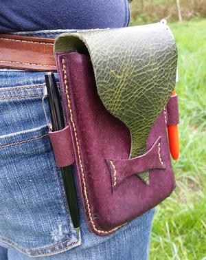 person wearing a purple and green steampunk leather cellphone holster