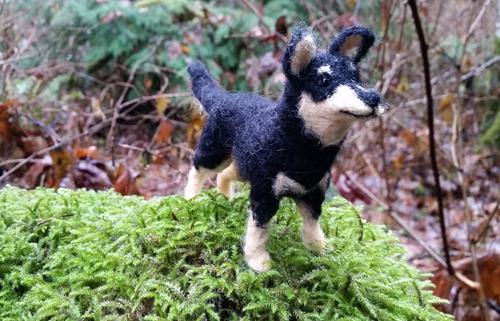 needle felted black and tan dog on a mossy log