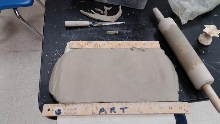 a rolling pin and slab of clay on an art table