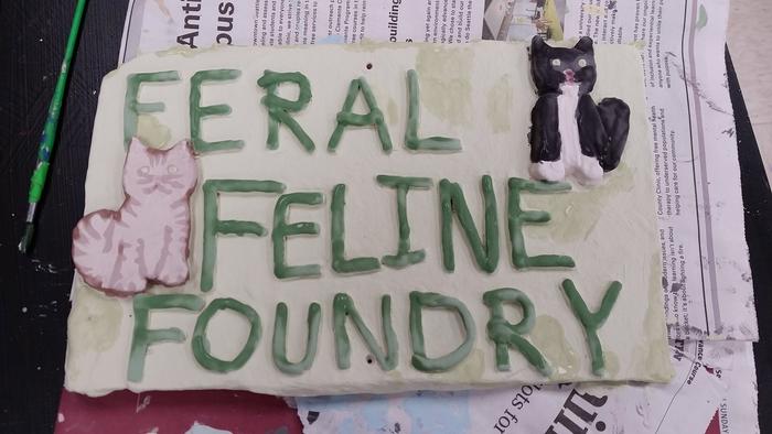 green clay sign with two cats reading feral feline foundry