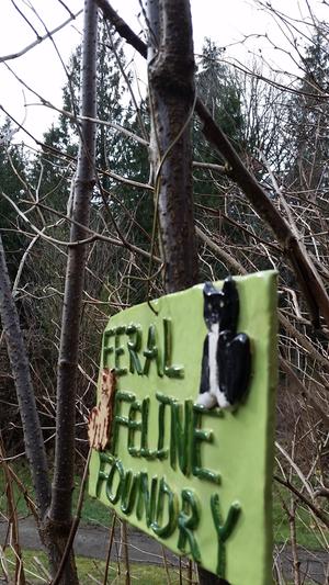 green clay sign hung with a coat hanger in the woods