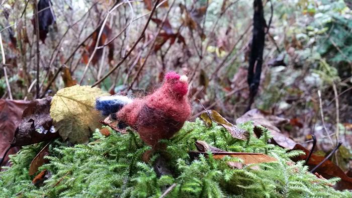 Needle-felted rooster on mossy log in the woods