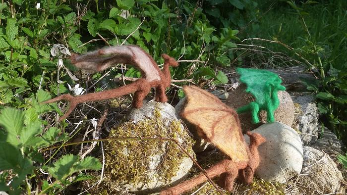 Bronze, brown and green pern dragons that are needle felted out of wool and sitting on rocks