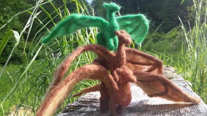 three needle felted dragons stacked on top of each other, on a log with natural background