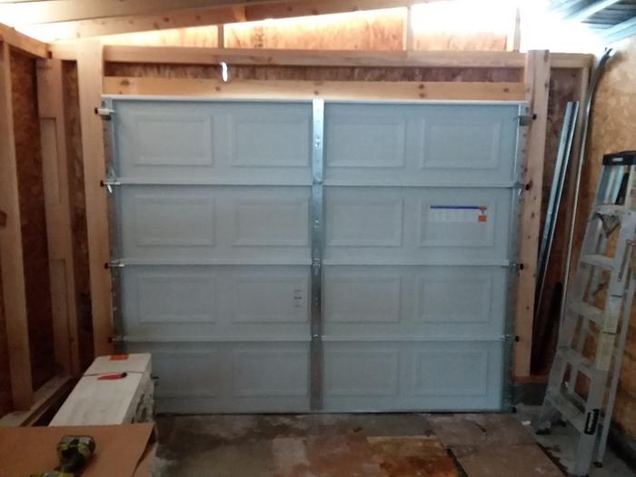 Put the door up and pin in place with nails. THEN add the rails. Helps to have a service door to escape the garage...