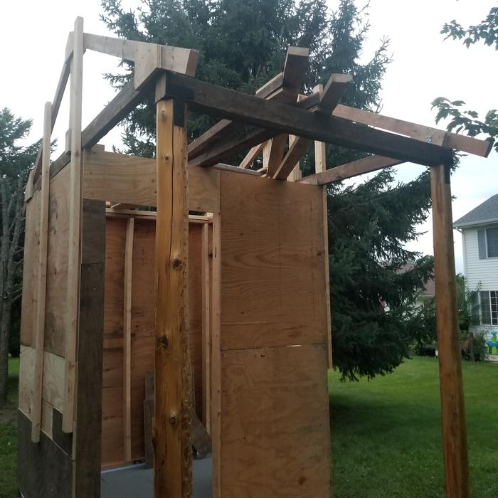 walls are up, some plywood is on to hold square, cedar logs are in and the header, trusses are going up