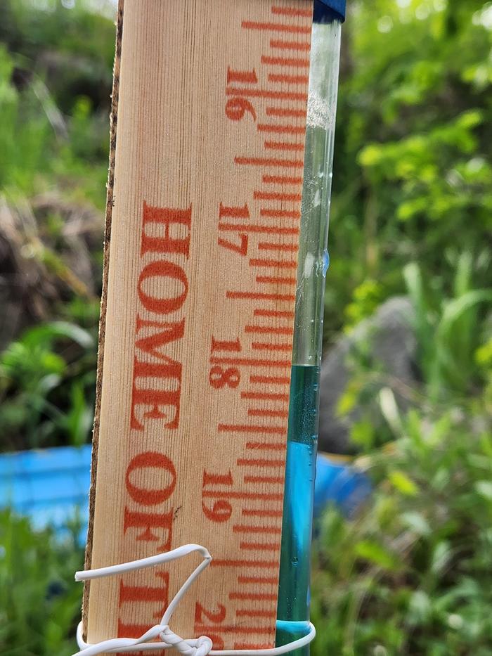 measuring stake with far end of tube showing level at middle of yardstick